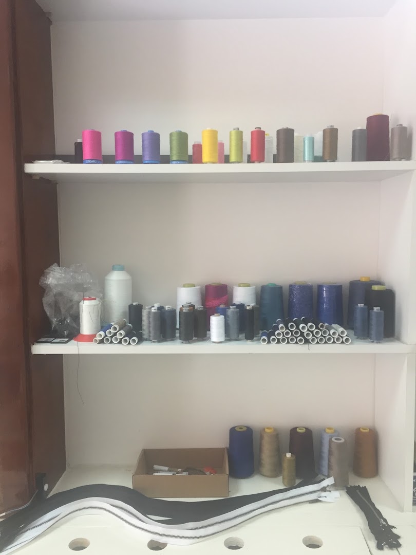 Planken vol garenspoelen in alle kleuren in het atelier